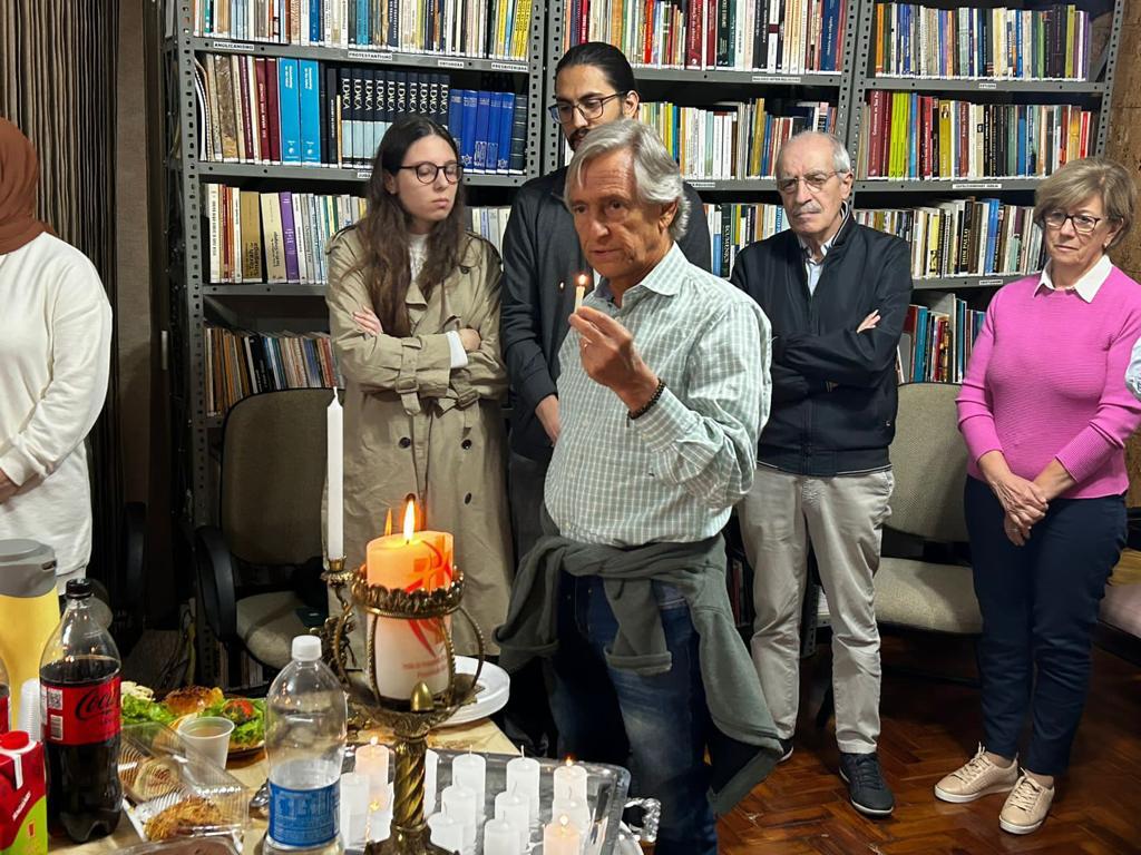 Membro das Famílias Abraâmicas segurando uma vela.